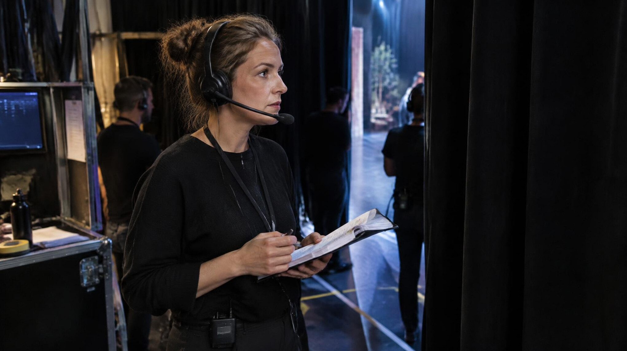 Stage manager coordinating scene timing with a script backstage